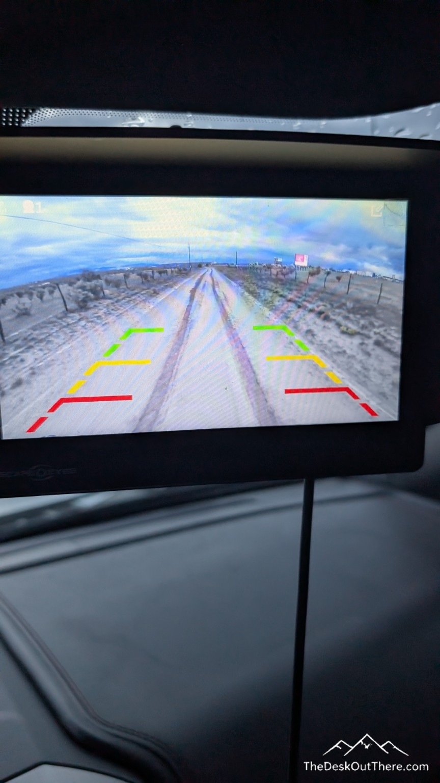 Rear camera monitor showing the muddy road behind the camper.