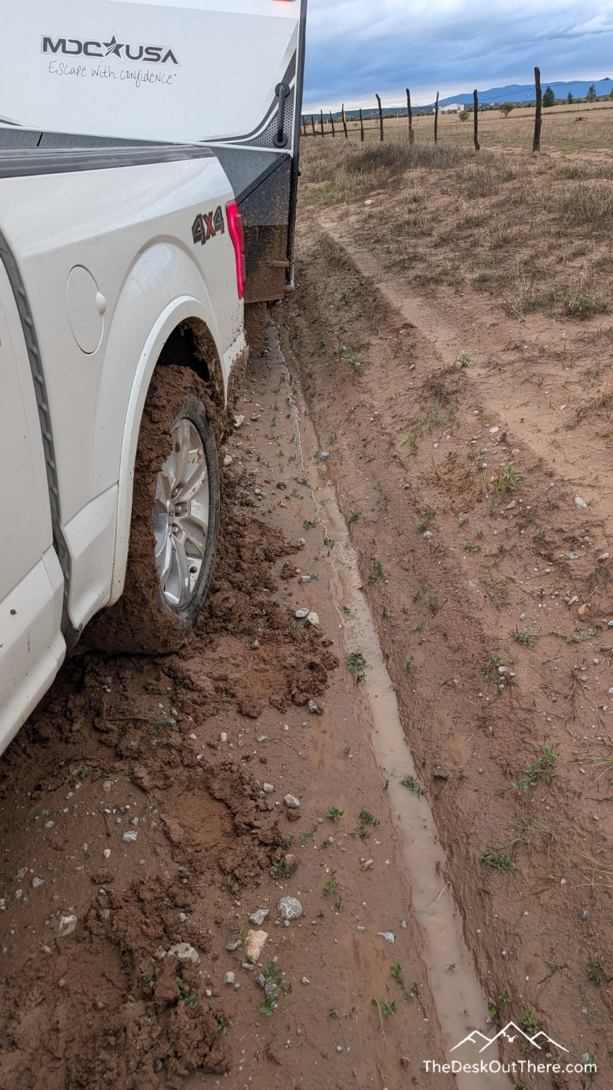 Mud-covered rear tire alongside a deep water-filled rut.