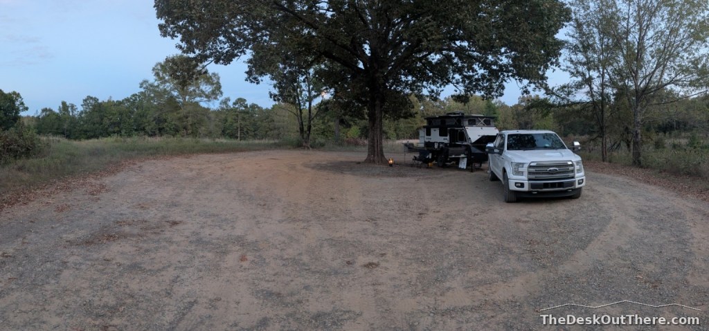 Truck and camper set up under a large tree at the final Arkansas campsite.