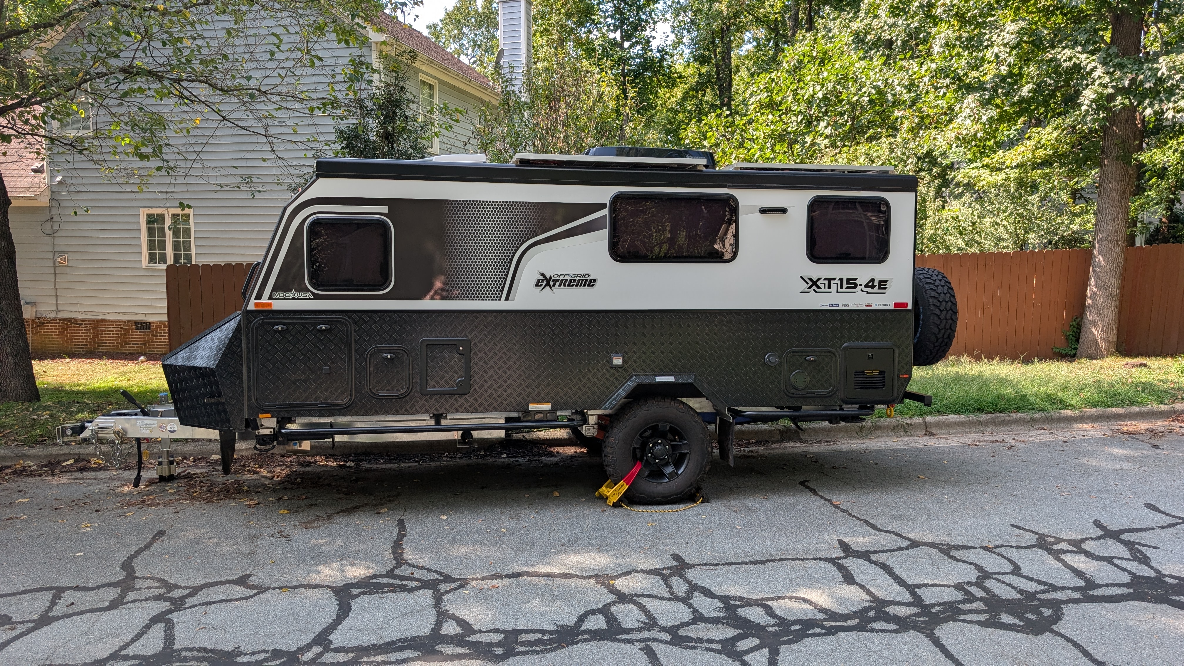 Side view of a camper trailer parked beside a house before the trip.