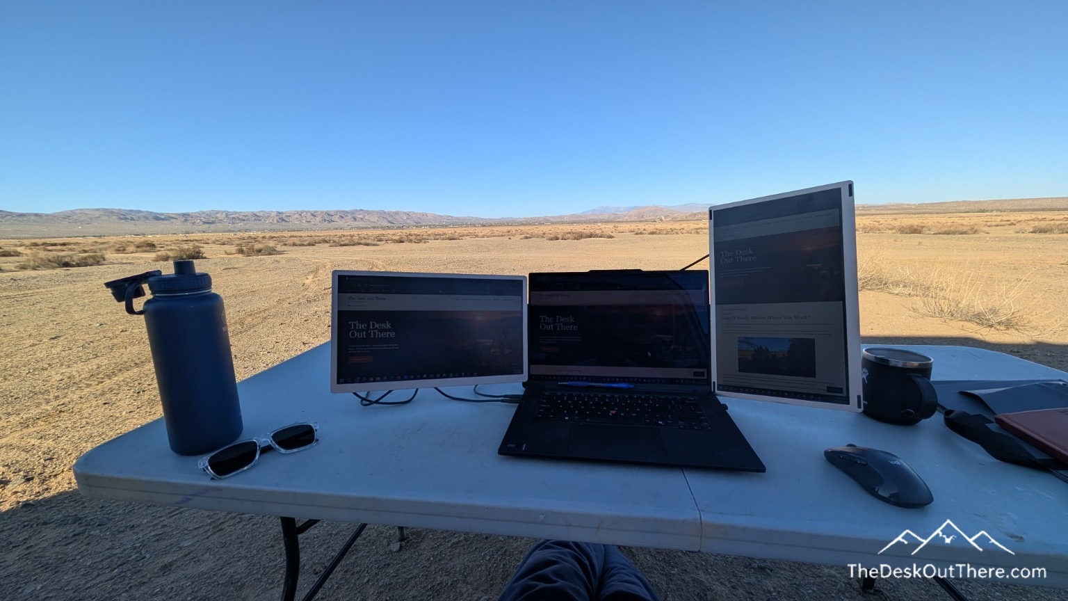 Three screens on the outdoor desk with a desert view