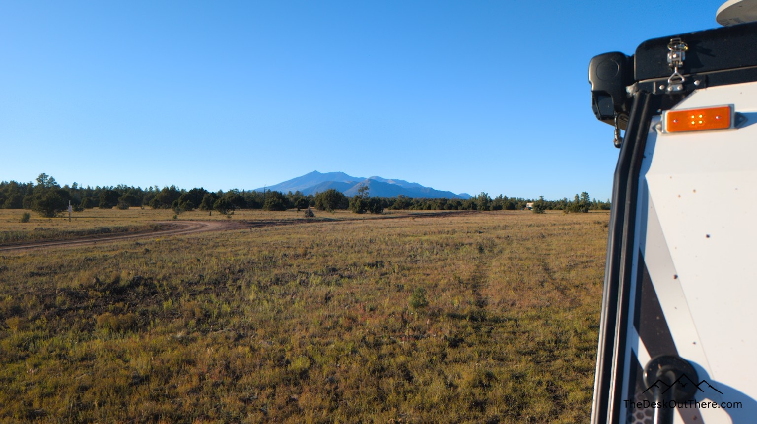 Open meadow and distant mountains beside the camper.